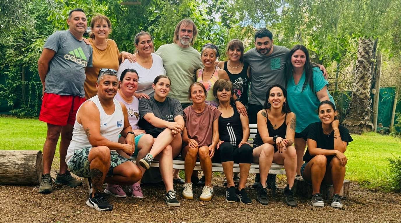 Foto grupal del equipo de IPSI: profesionales y colaboradores reunidos en un parque, sentados en un banco rodeado de árboles.
